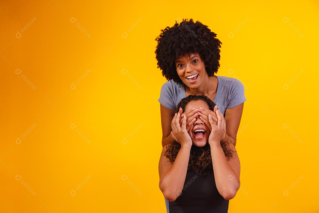 Filha tampado olhos de sua mãe sobre um fundo amarelo