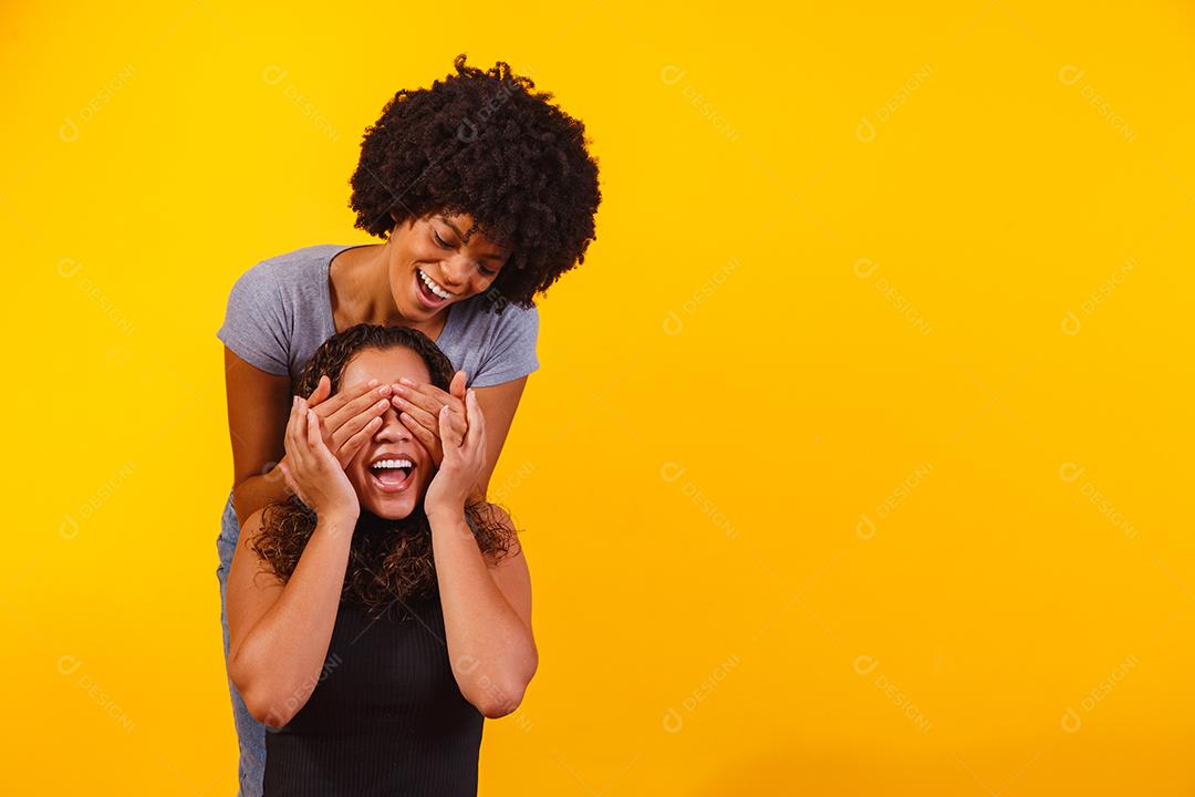 Filha tampado olhos de sua mãe sobre um fundo amarelo