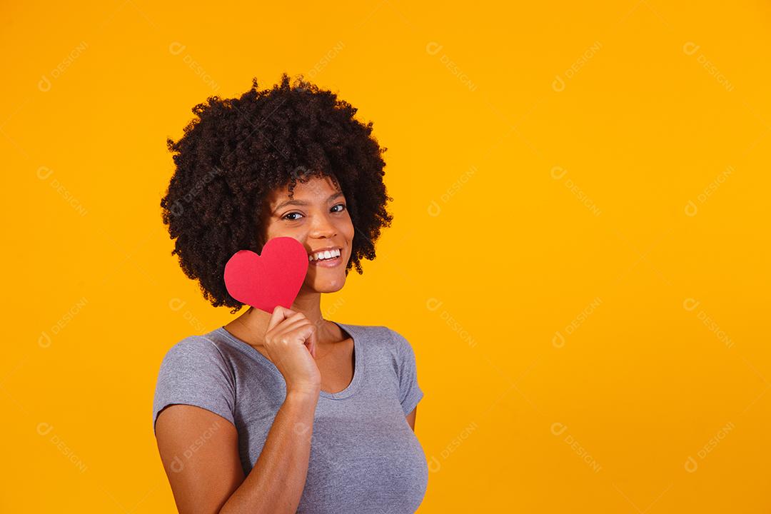 Retrato de menina isolada segurando um coração de papel sobre fundo amarelo