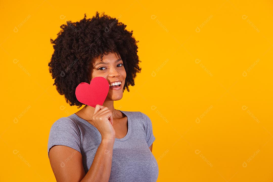 Retrato de menina isolada segurando um coração de papel sobre fundo amarelo