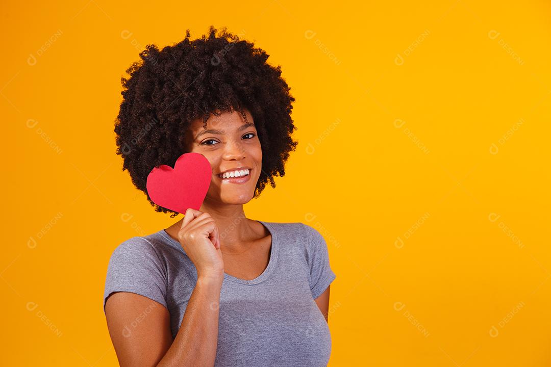 Retrato de menina isolada segurando um coração de papel sobre fundo amarelo