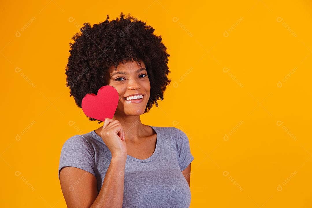 Retrato de menina isolada segurando um coração de papel sobre fundo amarelo