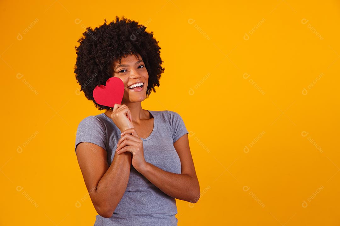 Retrato de menina isolada segurando um coração de papel sobre fundo amarelo