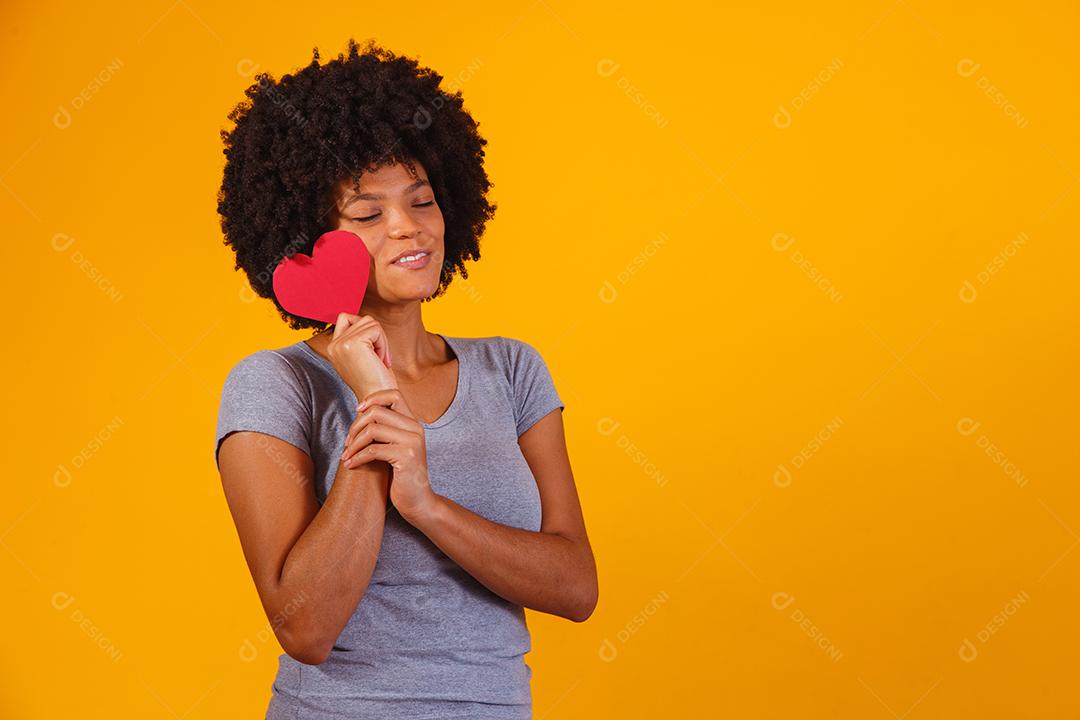 Retrato de menina isolada segurando um coração de papel sobre fundo amarelo
