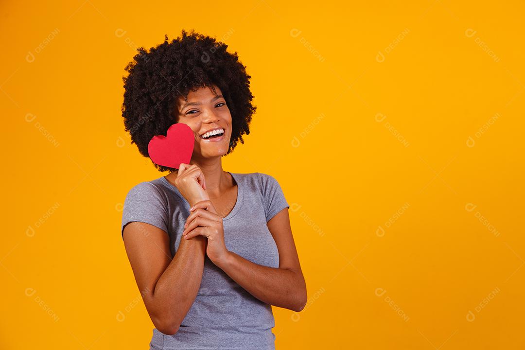 Retrato de menina isolada segurando um coração de papel sobre fundo amarelo
