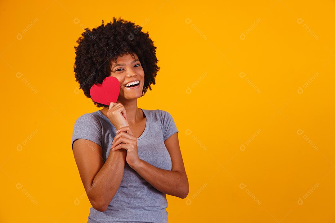 Retrato de menina isolada segurando um coração de papel sobre fundo amarelo