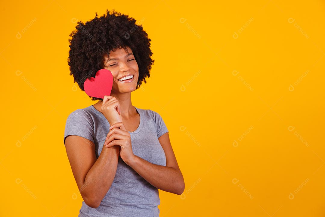 Retrato de menina isolada segurando um coração de papel sobre fundo amarelo