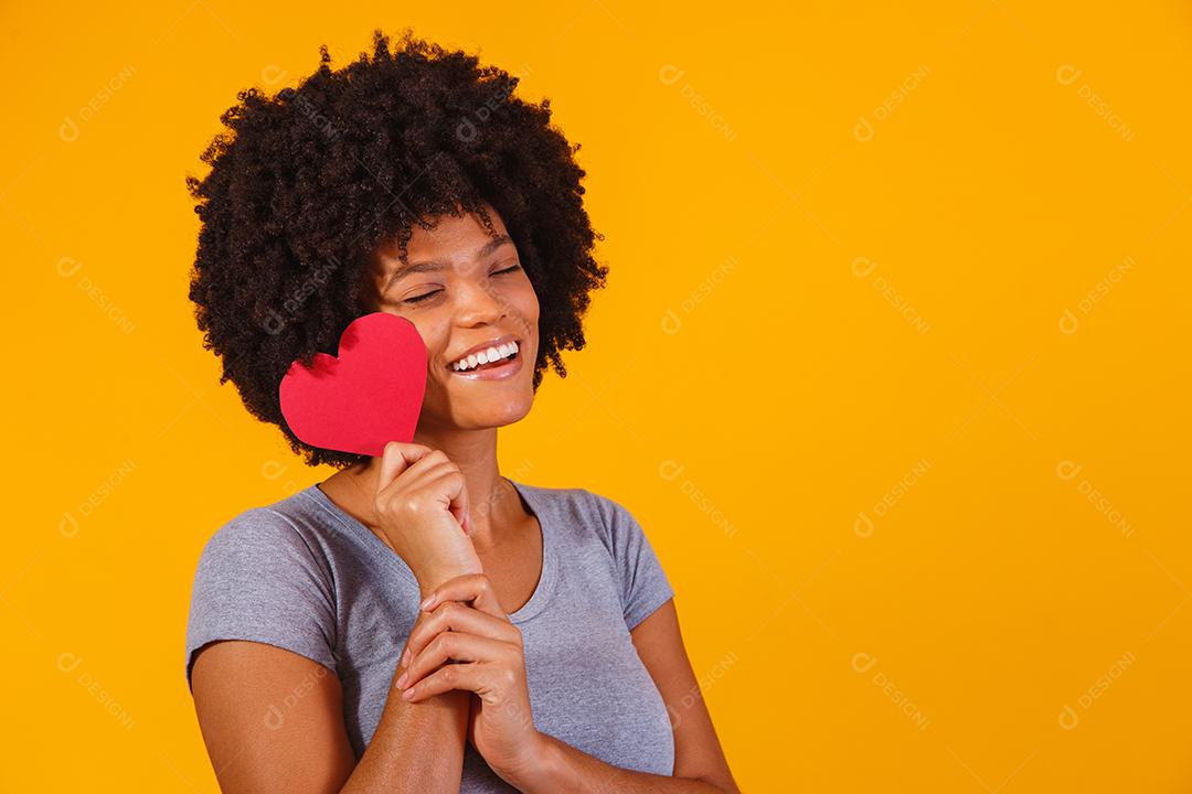 Retrato de menina isolada segurando um coração de papel sobre fundo amarelo