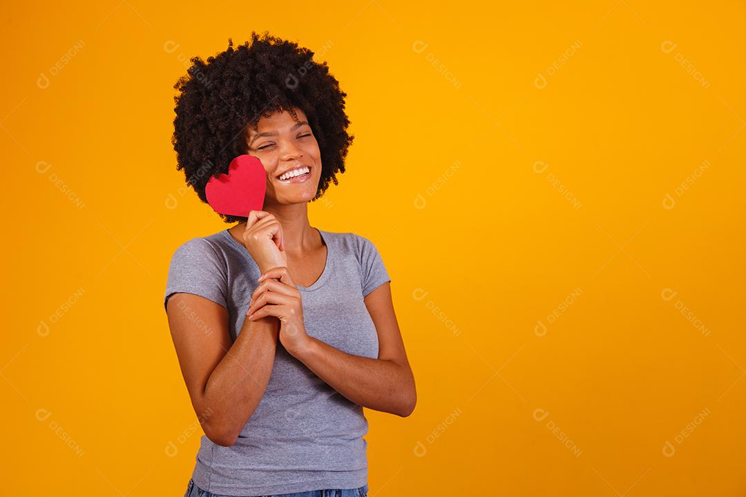 Retrato de menina isolada segurando um coração de papel sobre fundo amarelo