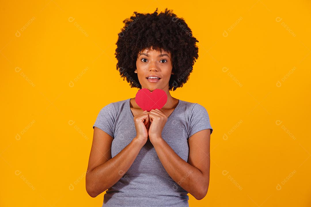 Retrato de menina isolada segurando um coração de papel sobre fundo amarelo
