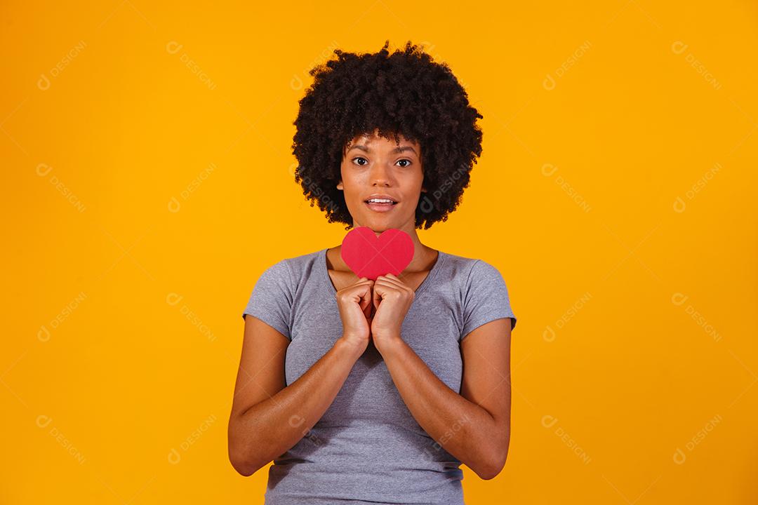 Retrato de menina isolada segurando um coração de papel sobre fundo amarelo