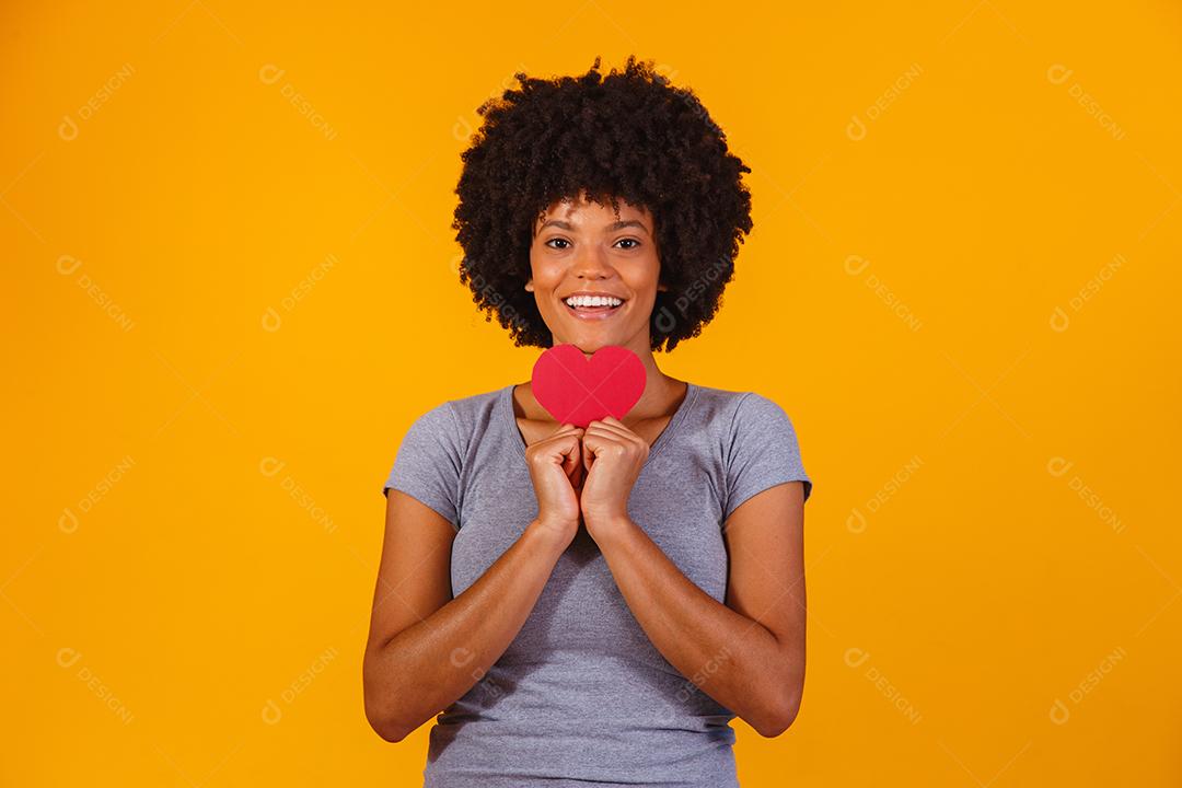 Retrato de menina isolada segurando um coração de papel sobre fundo amarelo