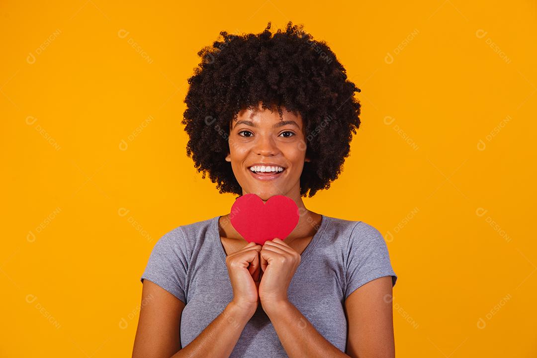 Retrato de menina isolada segurando um coração de papel sobre fundo amarelo