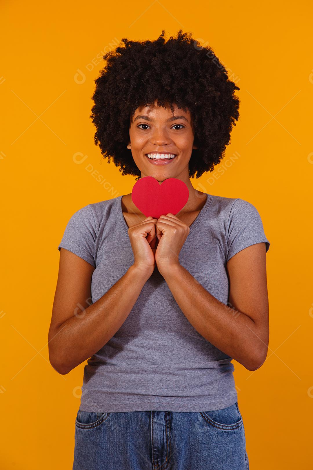 Retrato de menina isolada segurando um coração de papel sobre fundo amarelo