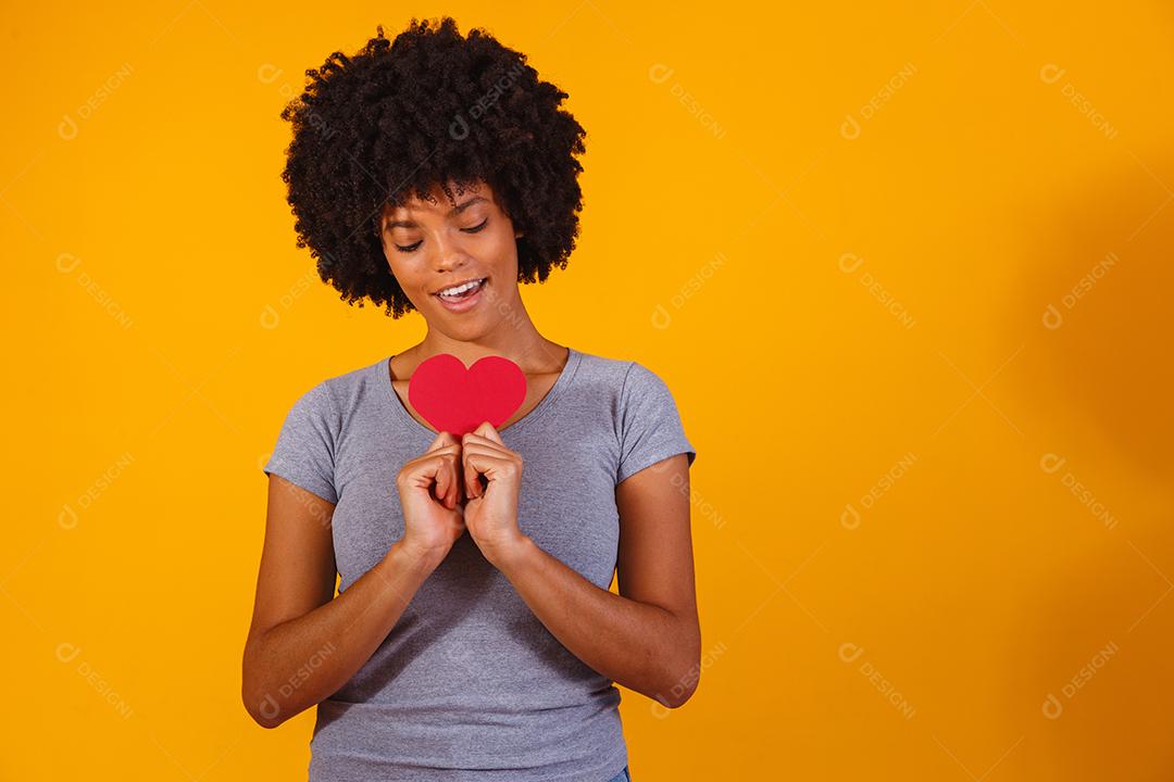 Portrait of isolated girl holding paper heart on yellow background