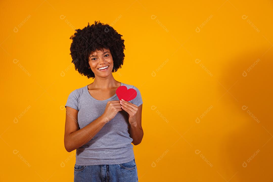 Retrato de menina isolada segurando um coração de papel sobre fundo amarelo