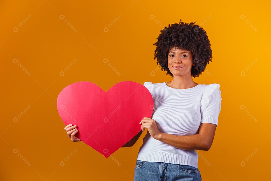 Smiling Afro woman holding a big red heart card