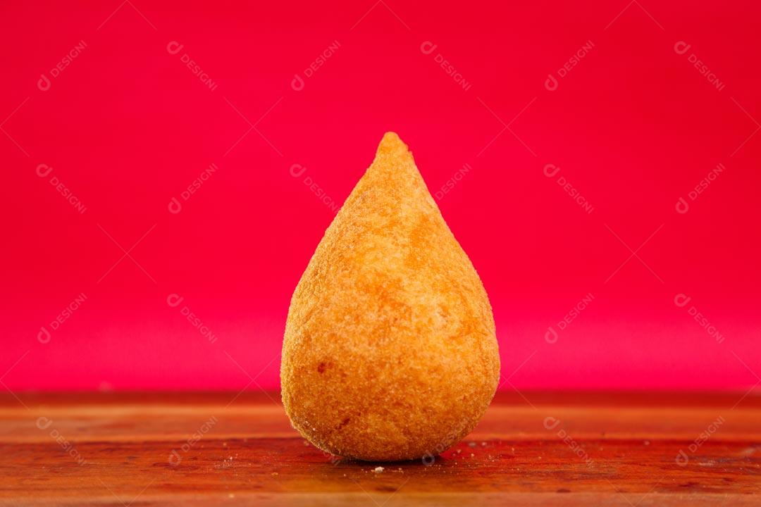 Coxinhas sobre mesa com temperos verdes fundo vermelho