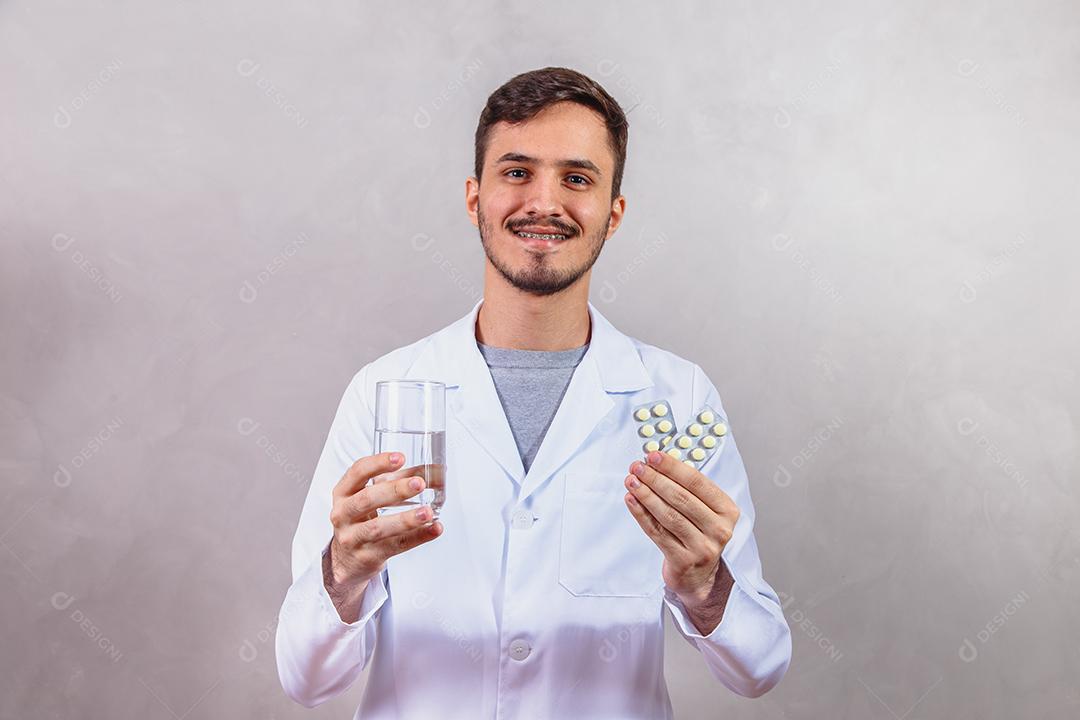 Médico segurando o copo de água e comprimidos