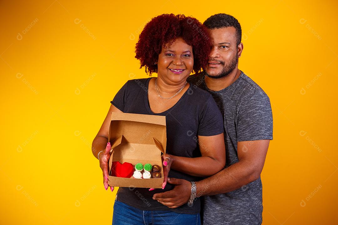 Casal de namorados afro com caixa de doces fazendo surpresa