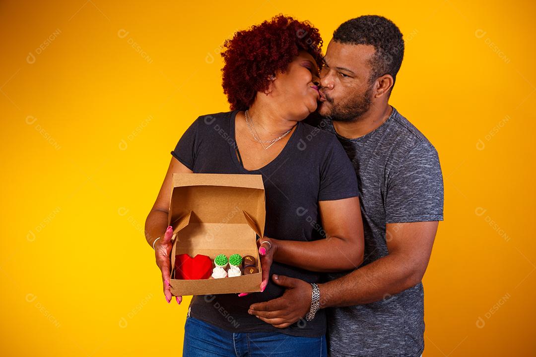 Casal de namorados afro com caixa de doces fazendo surpresa