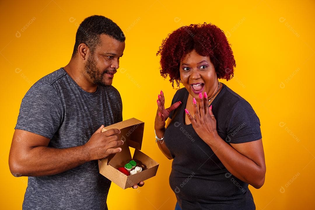Casal de namorados afro com caixa de doces fazendo surpresa