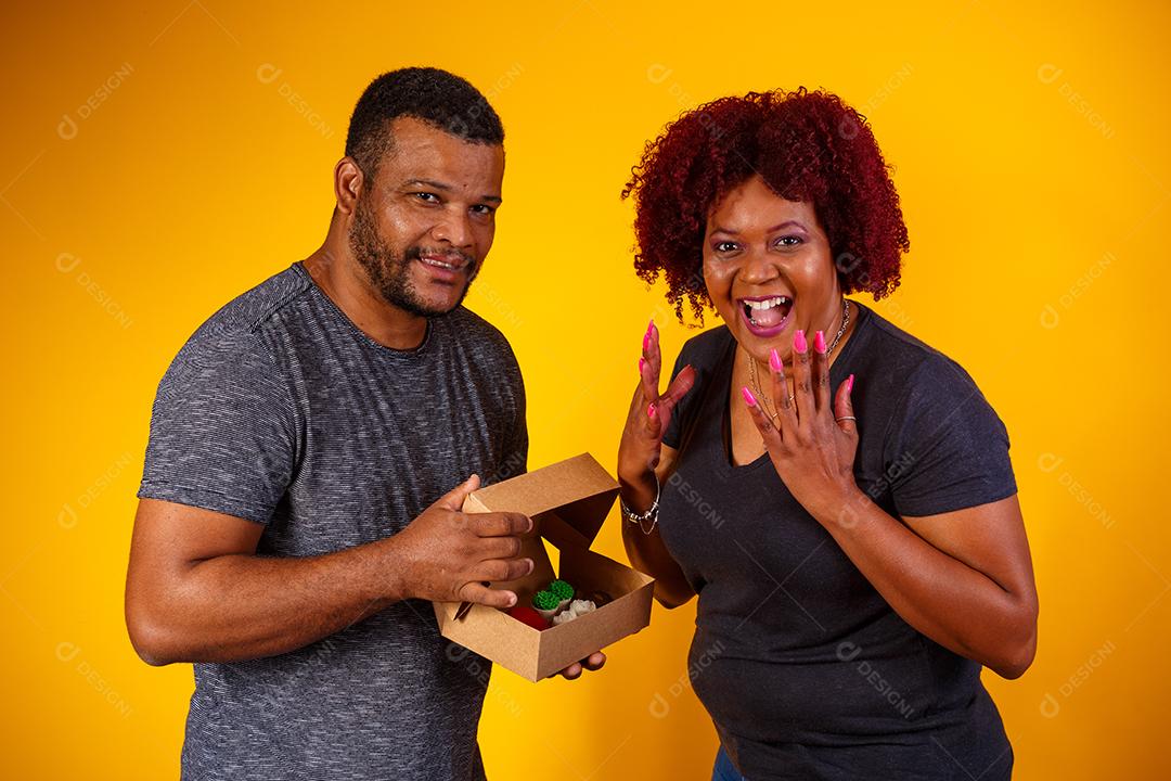 Casal de namorados afro com caixa de doces fazendo surpresa