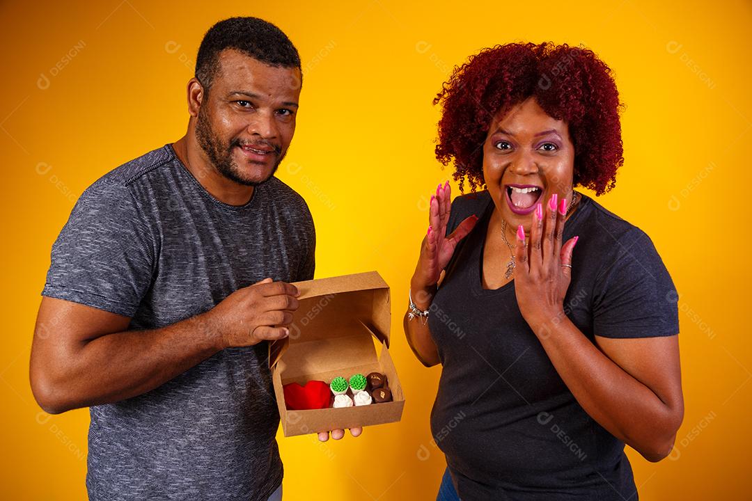 Casal de namorados afro com caixa de doces fazendo surpresa