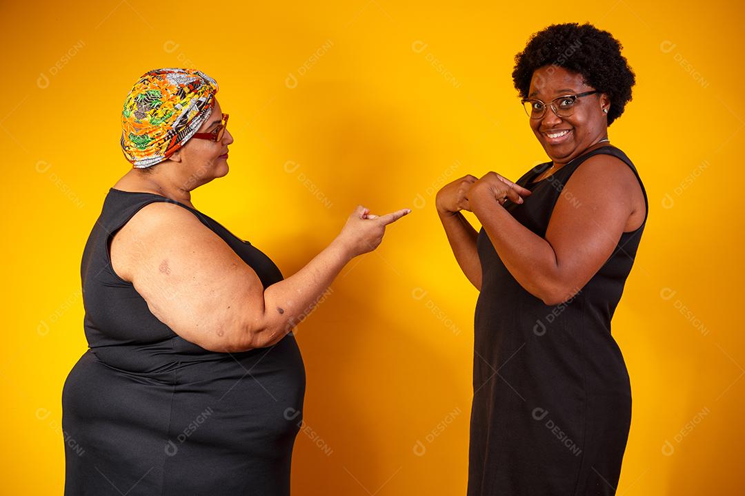 Duas Mulheres Amigas Olhando para Câmera e a Outra Apontando