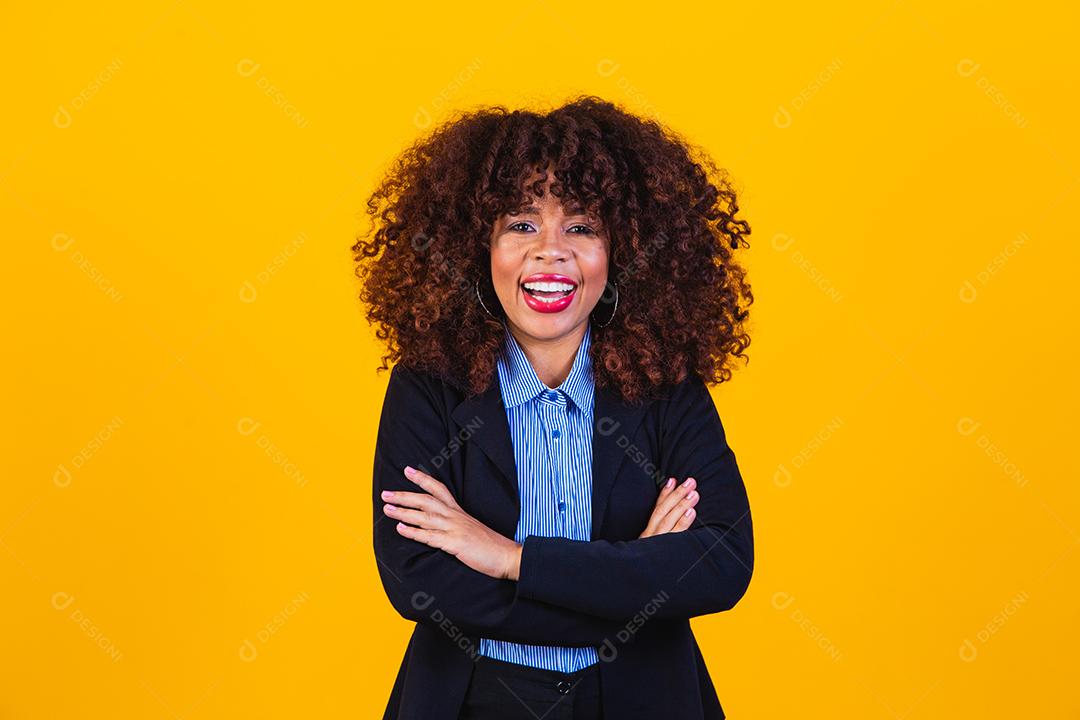 Mulher de cabelo cacheado com blazer preto em fundo amarelo