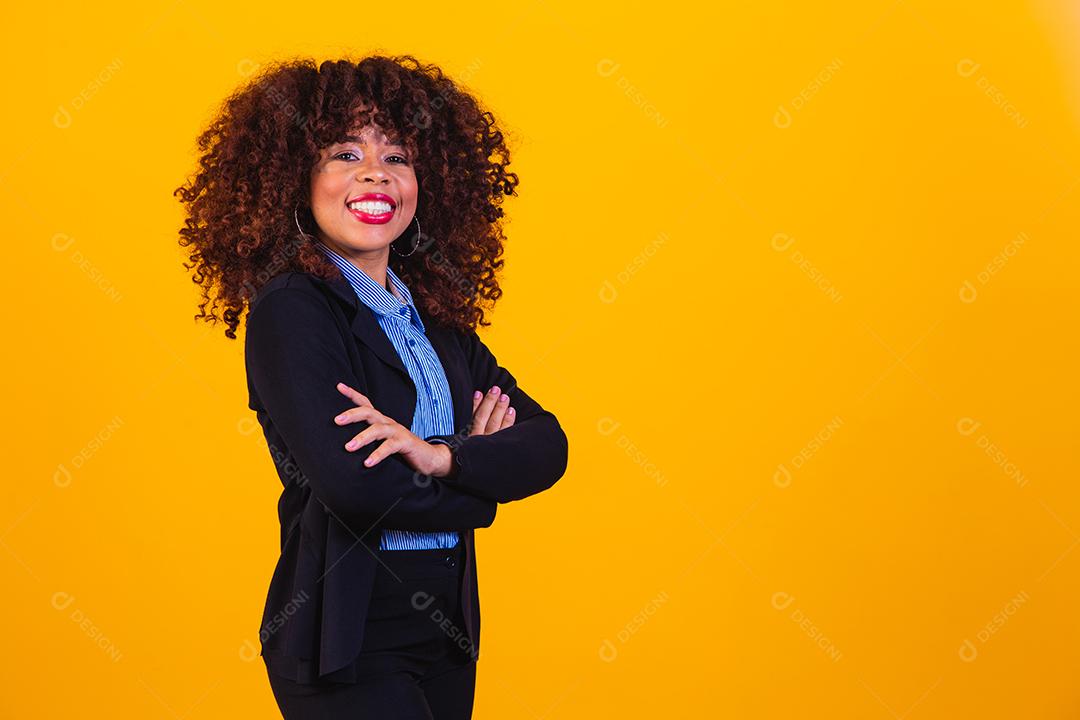 Mulher de cabelo cacheado com blazer preto em fundo amarelo