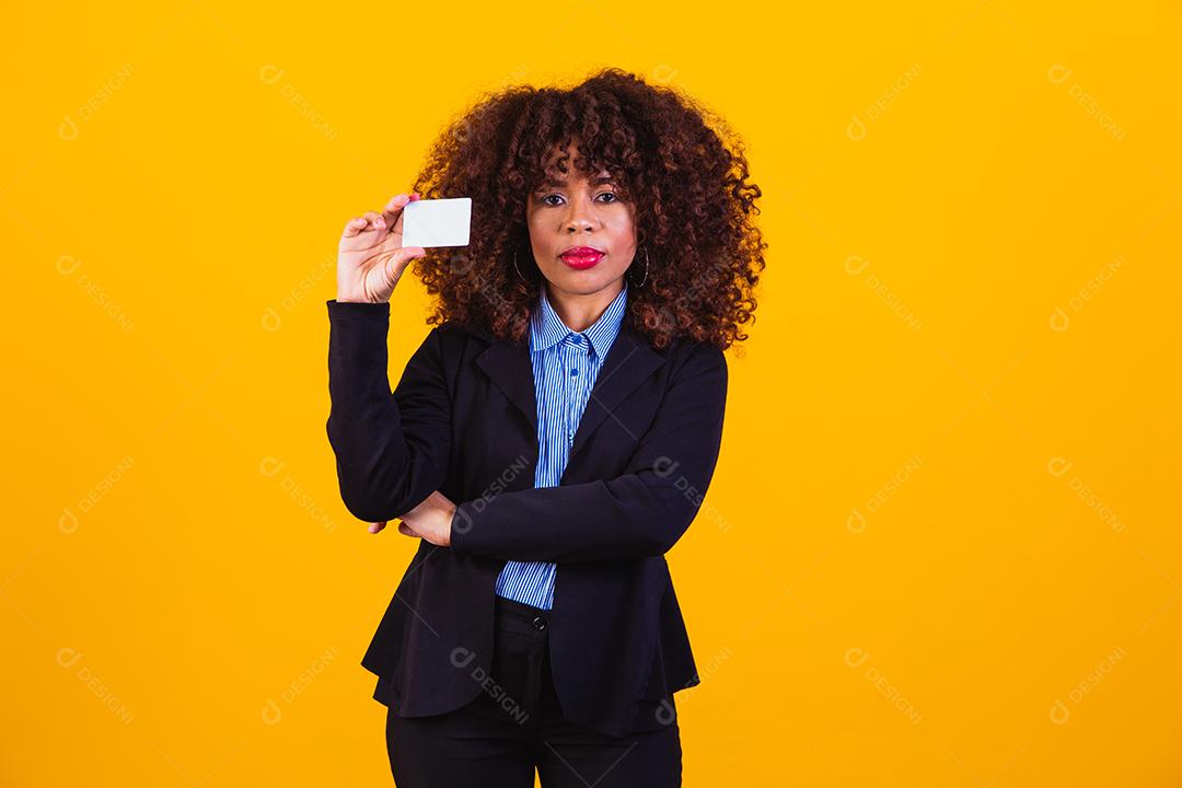 Mulher de cabelo cacheado com blazer preto em fundo amarelo