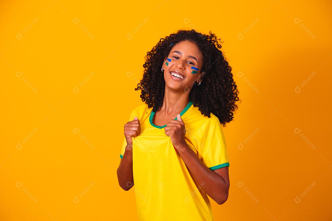 Mulher de cabelo cacheado e camiseta amarela do brasil em fundo amarelo