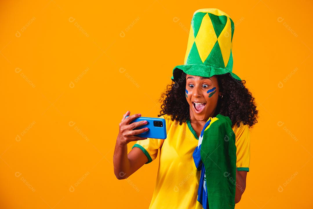 Fã brasileiro assistindo futebol no celular