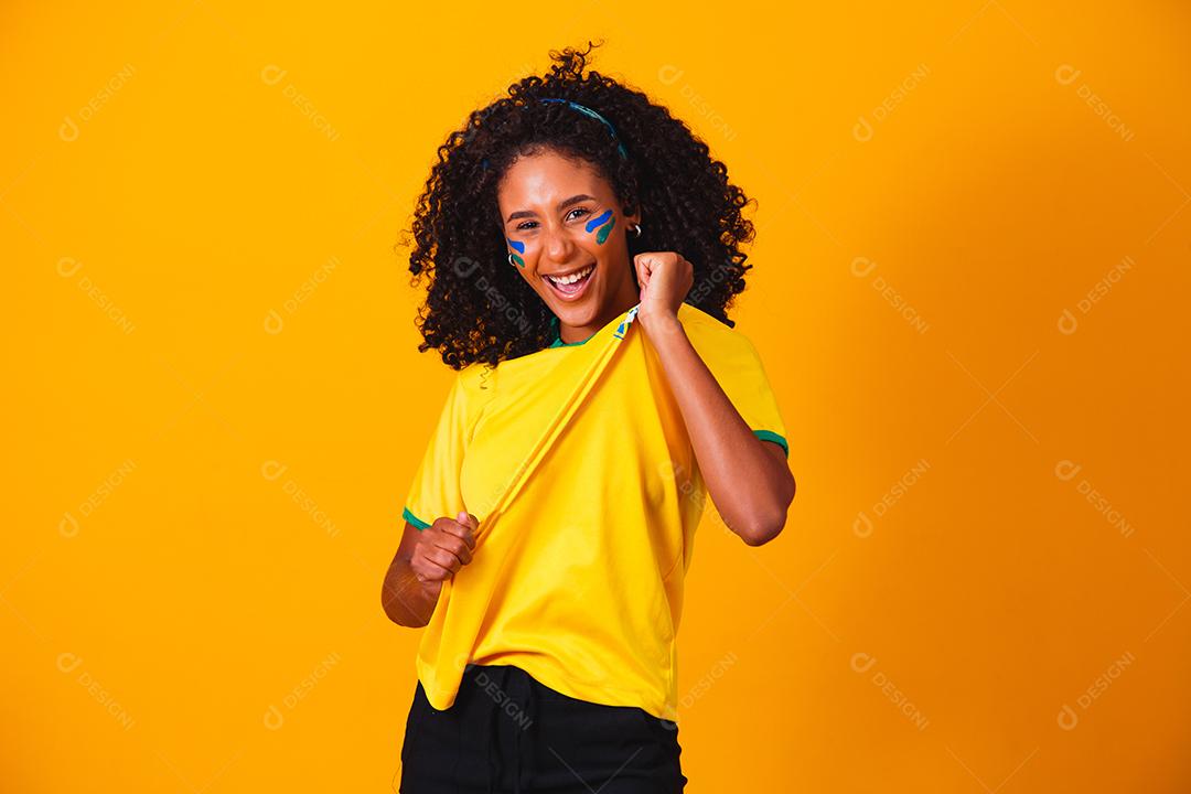 Mulher de cabelo cacheado e camiseta amarela do brasil em fundo amarelo