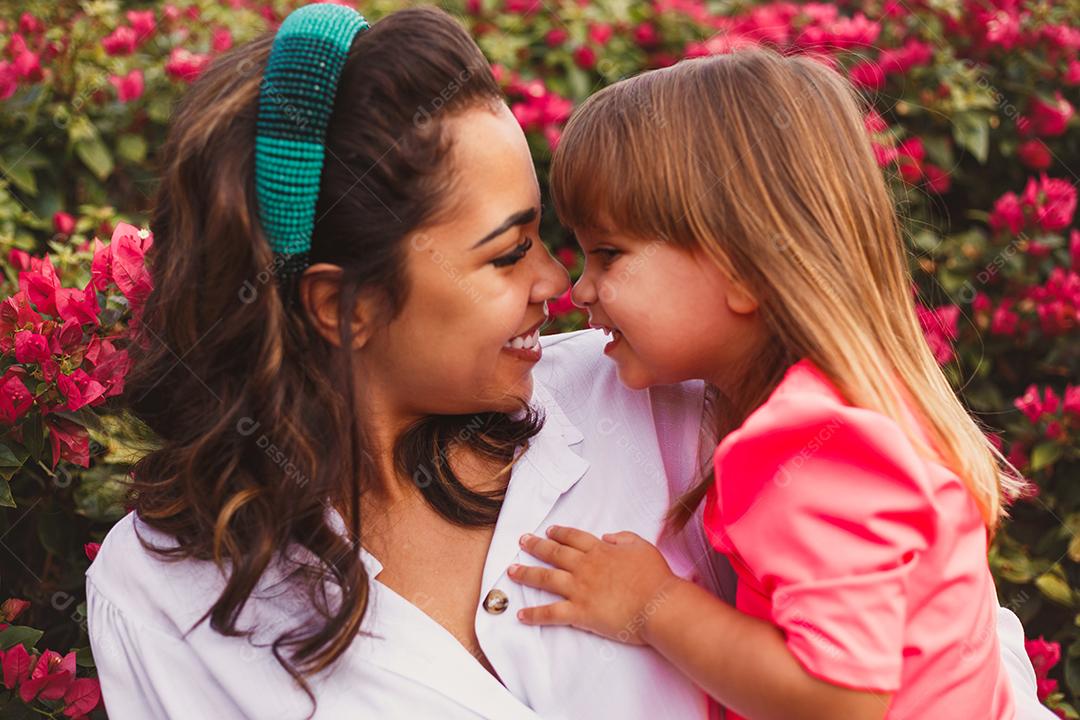 Mãe e filha juntas em praça florida em fim de dia