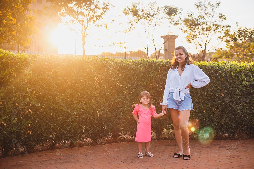 Mãe e filha juntas em praça florida em fim de dia