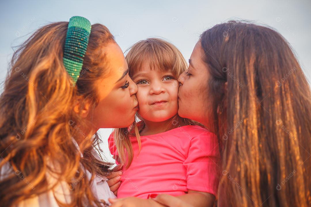 Mãe e filhas juntas em praça florida em fim de dia