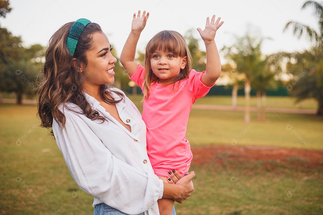 Mãe e filhas juntas em praça florida em fim de dia