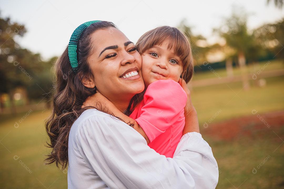 Mãe e filha junta em praça florida em fim de dia