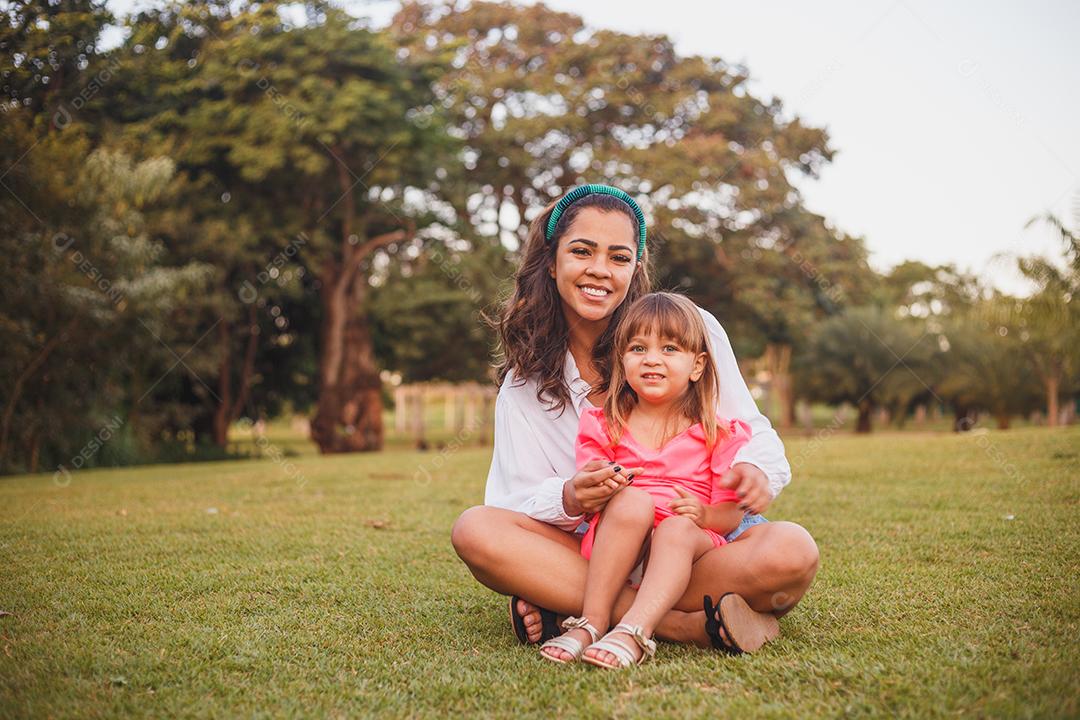 Mãe e filha junta em praça florida em fim de dia