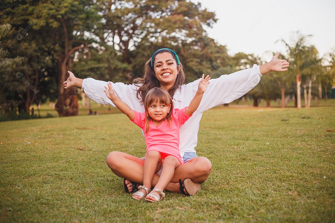Mãe e filha junta em praça florida em fim de dia