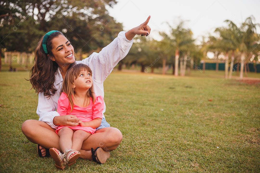 Mãe e filha junta em praça florida em fim de dia