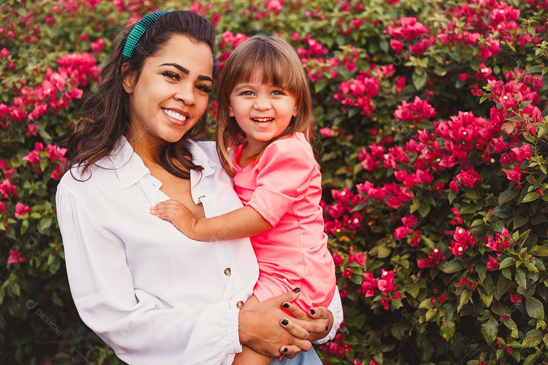 Mãe e filha junta em praça florida em fim de dia