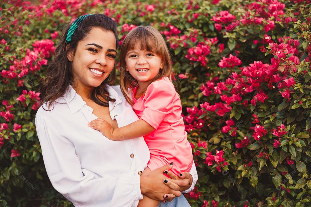 Mãe e filha junta em praça florida em fim de dia