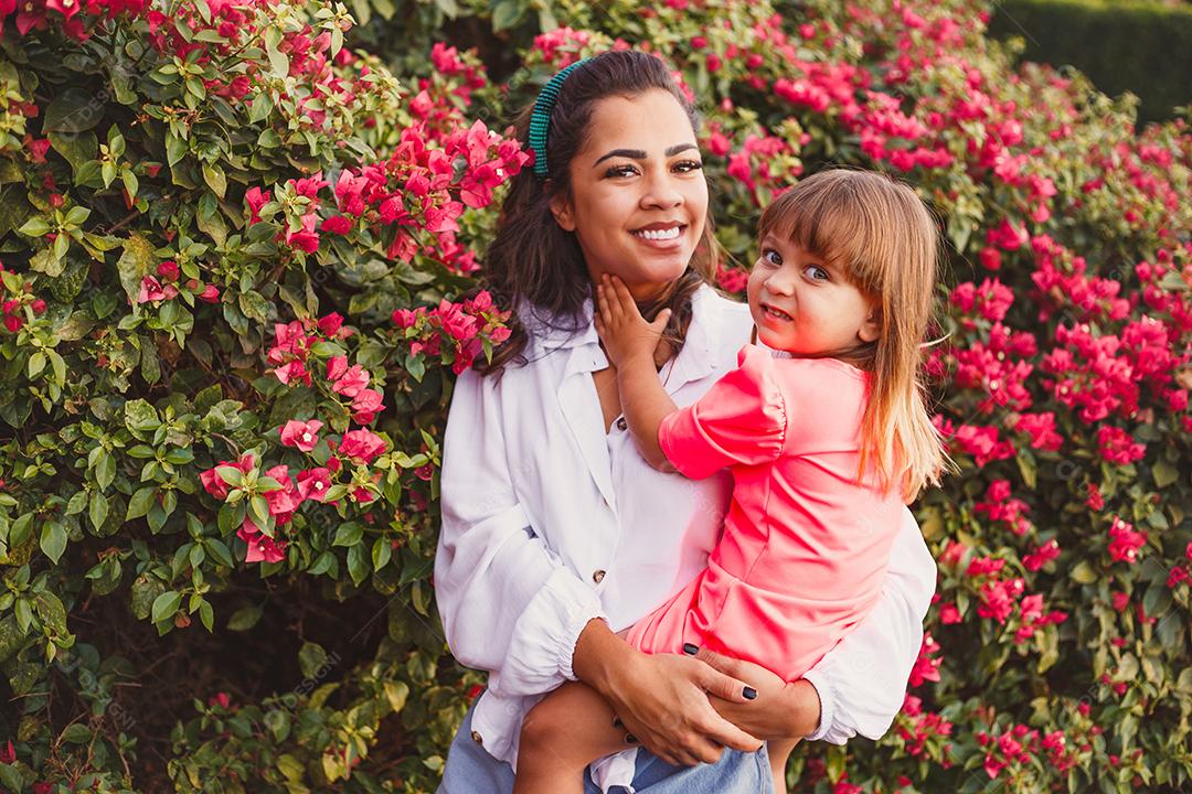 Mãe e filha junta em praça florida em fim de dia