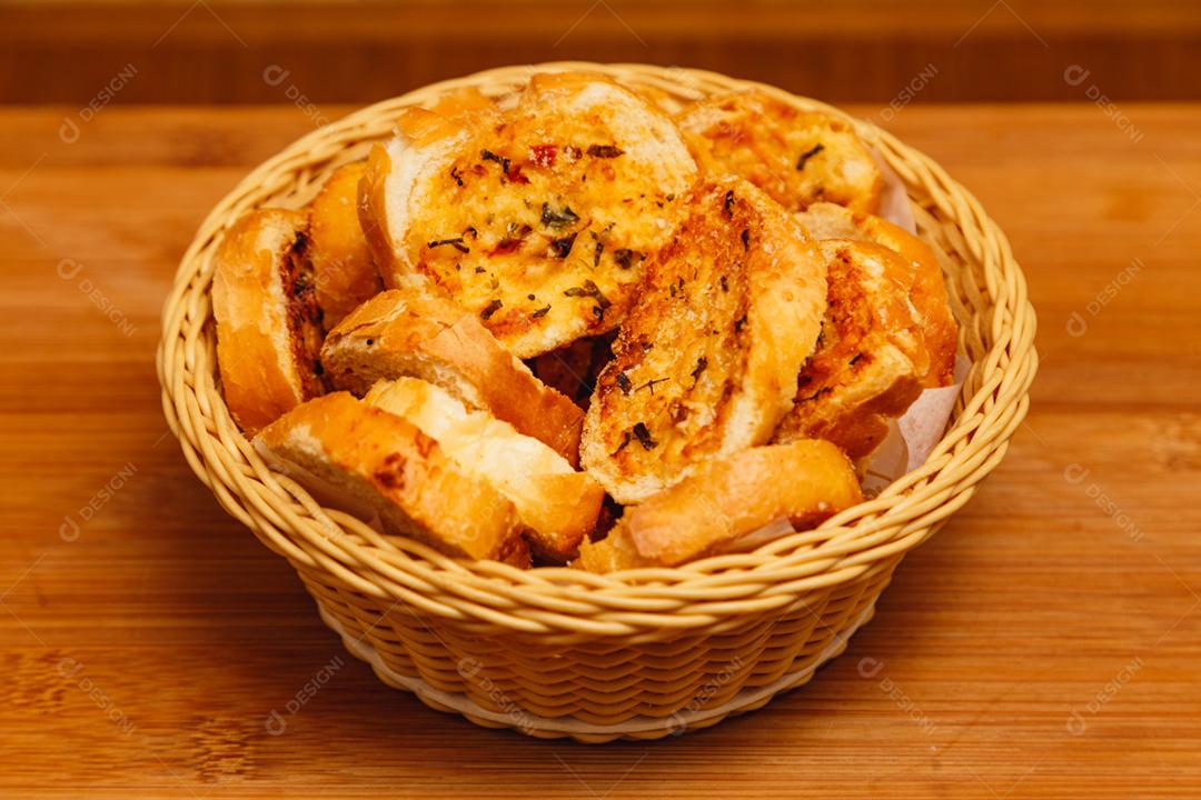 cesta com torradas com manteiga, sobre uma mesa de madeira, com fundo amadeirado