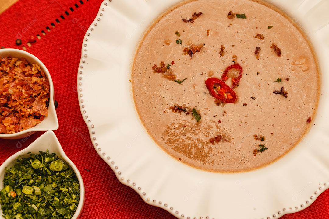 Delicioso caldo de feijão, Sopa de feijão, com fundo de madeira, fundo de tecido vermelho, com torradas, salsa