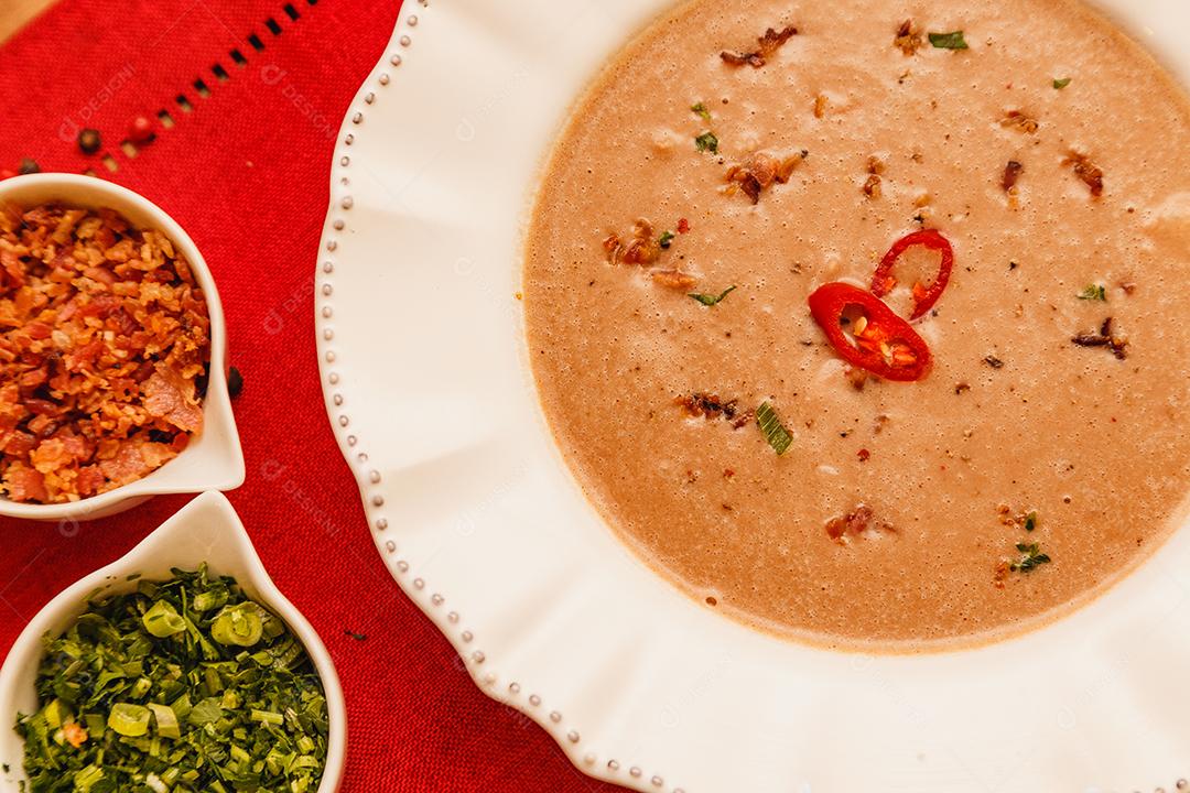 Delicioso caldo de feijão, Sopa de feijão, com fundo de madeira, fundo de tecido vermelho, com torradas, salsa