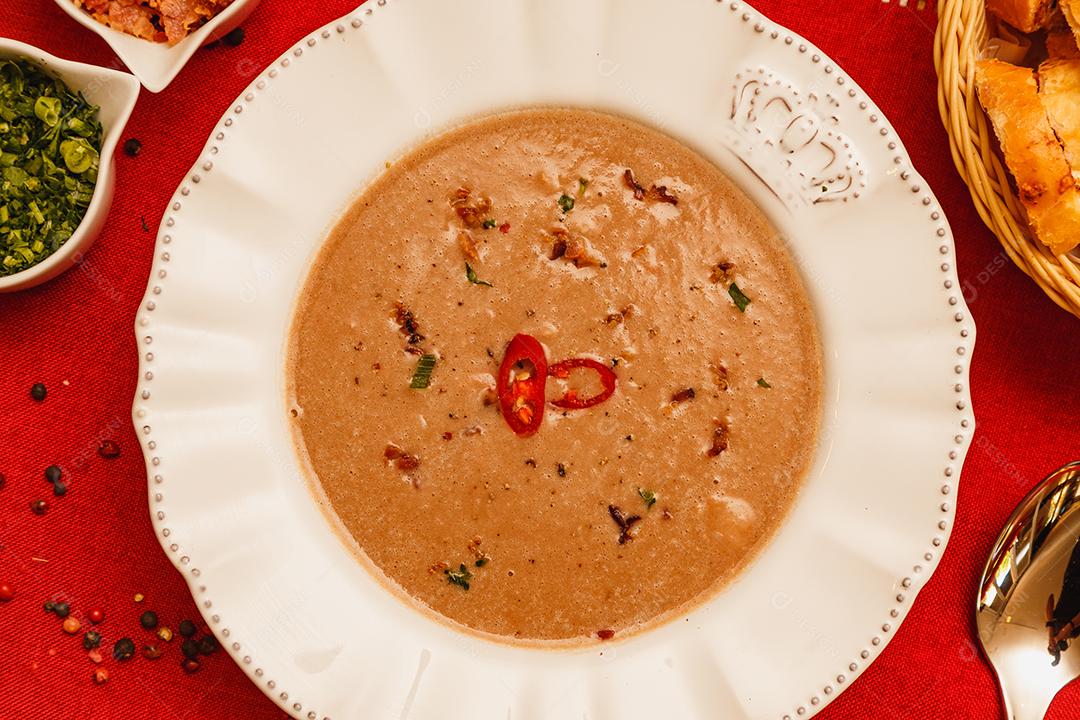 Delicioso caldo de feijão, Sopa de feijão, com fundo de madeira, fundo de tecido vermelho, com torradas, salsa